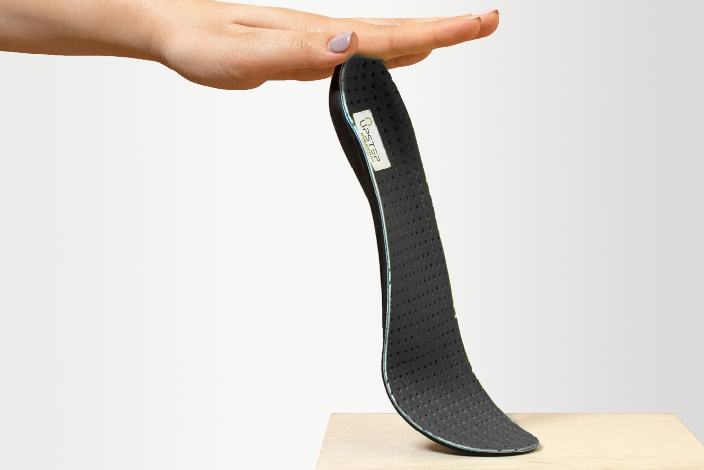 A hand holding a black insole for viewing