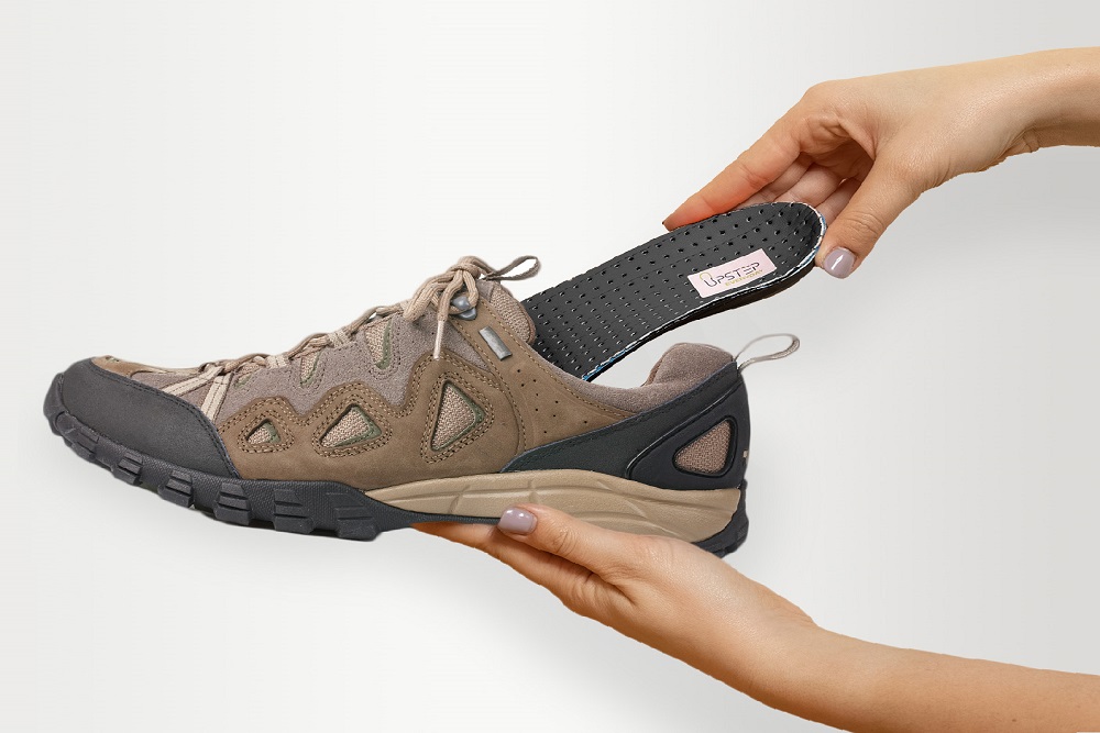 A hand placing an insole into a hiking boot