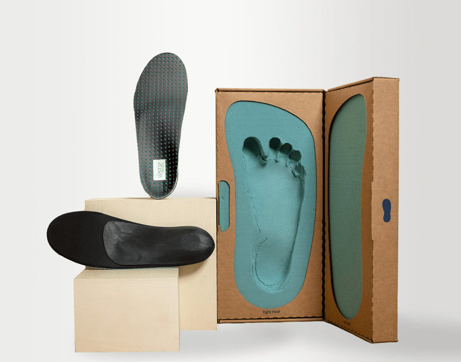 Two black insoles next to a foot impression kit